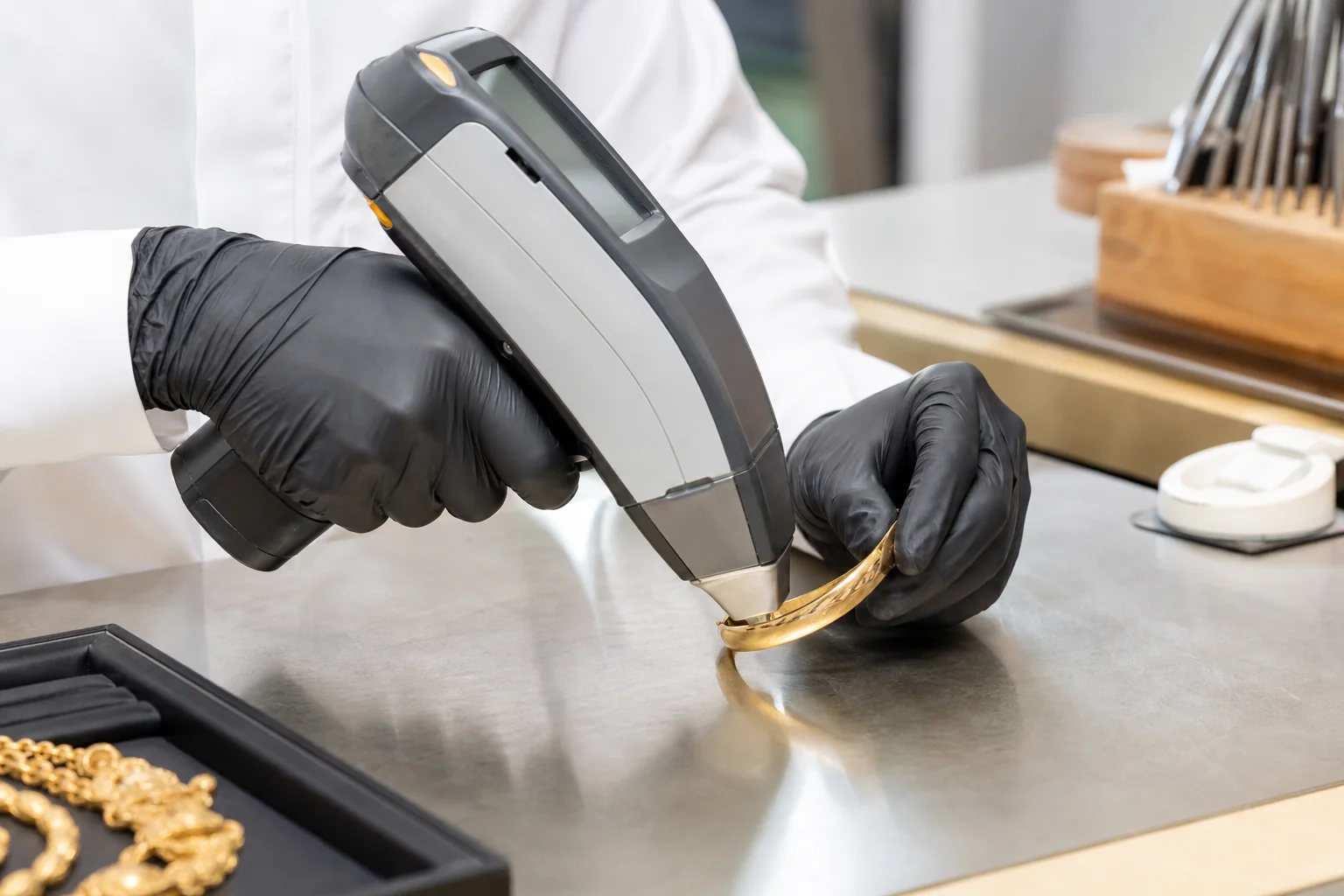 مختص يفحص سواراً ذهبياً بجهاز الأشعة السينية المحمول XRF داخل ورشة مجوهرات